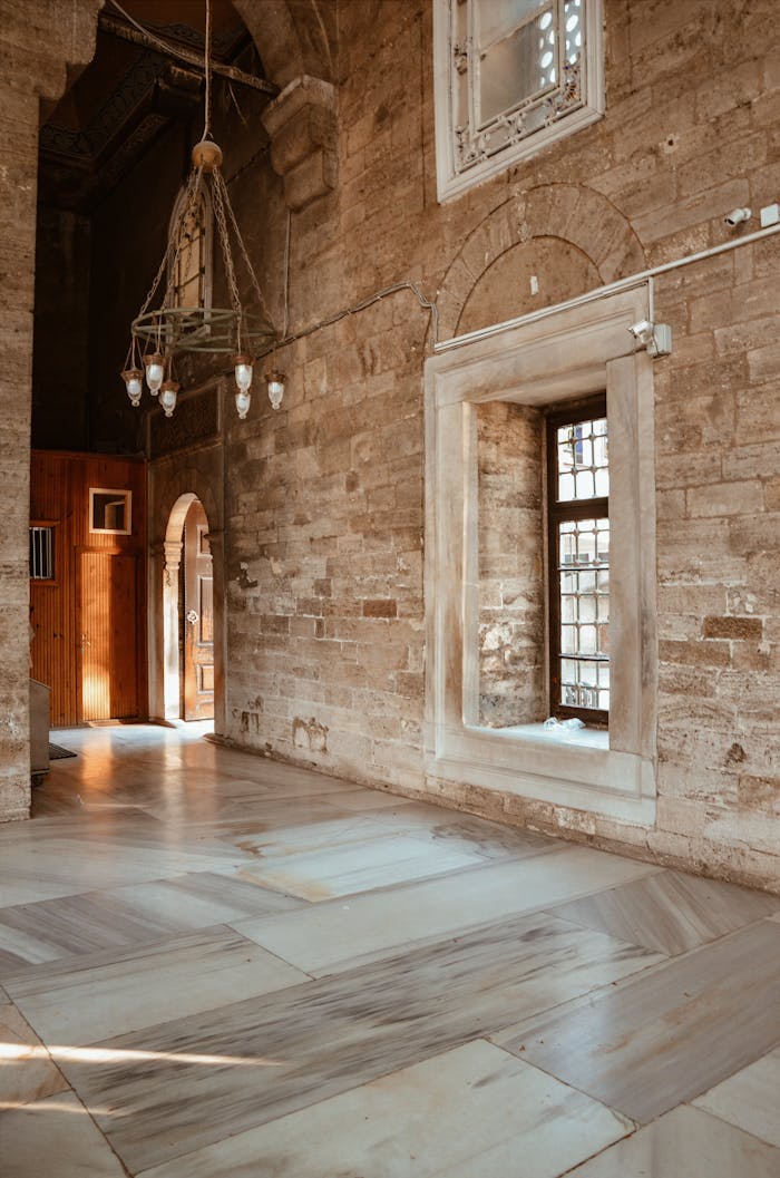 my-path Elegant stone hallway with natural light, featuring arched doorways and vintage chandelier.