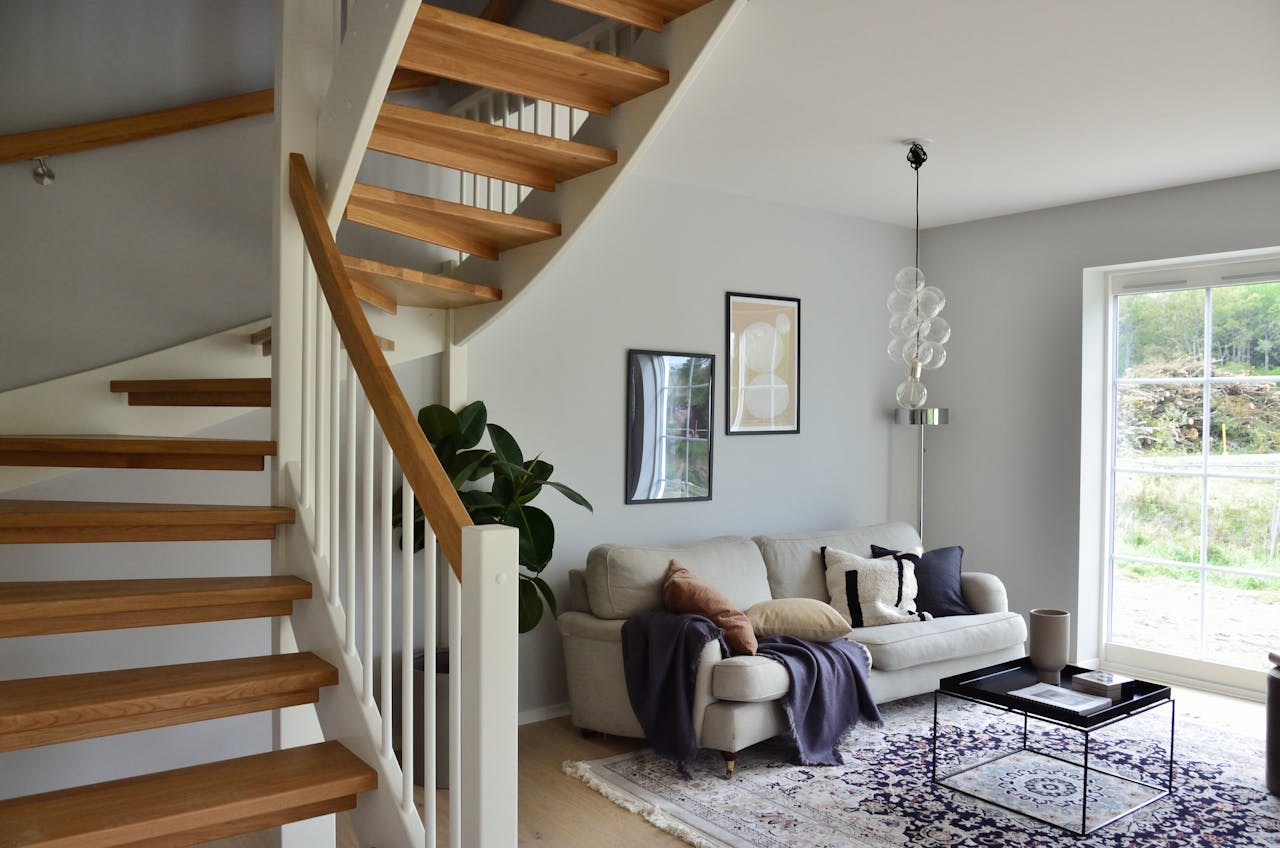 about-img Stylish Scandinavian living room featuring a wooden staircase, cozy sofa, and modern decor.